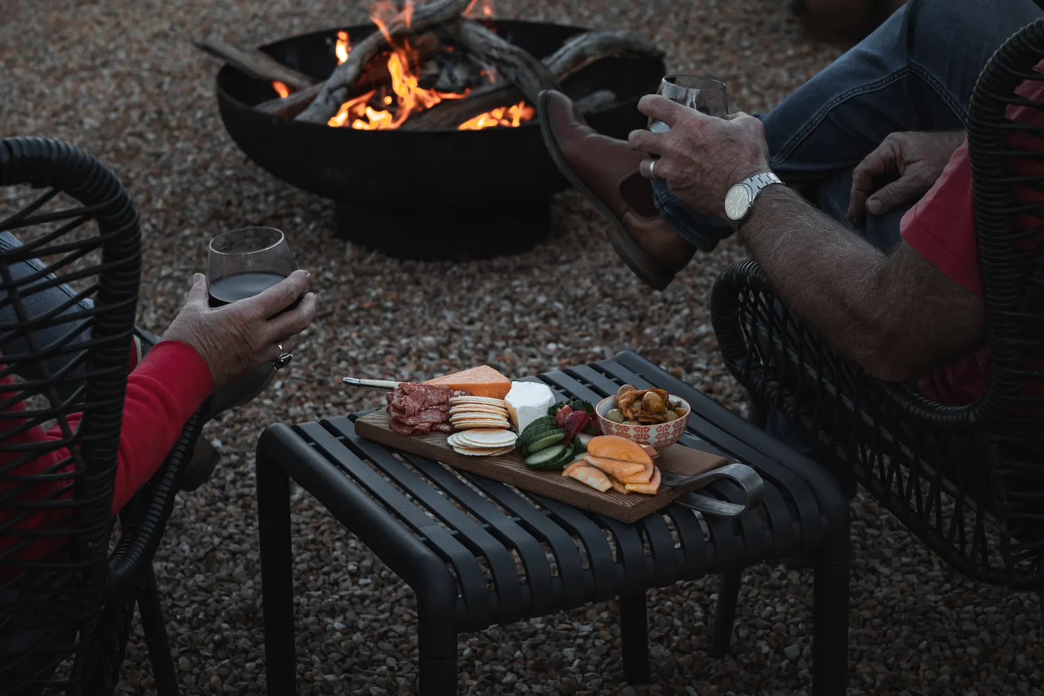 The fire pit burning at dusk, with chairs drawn around it