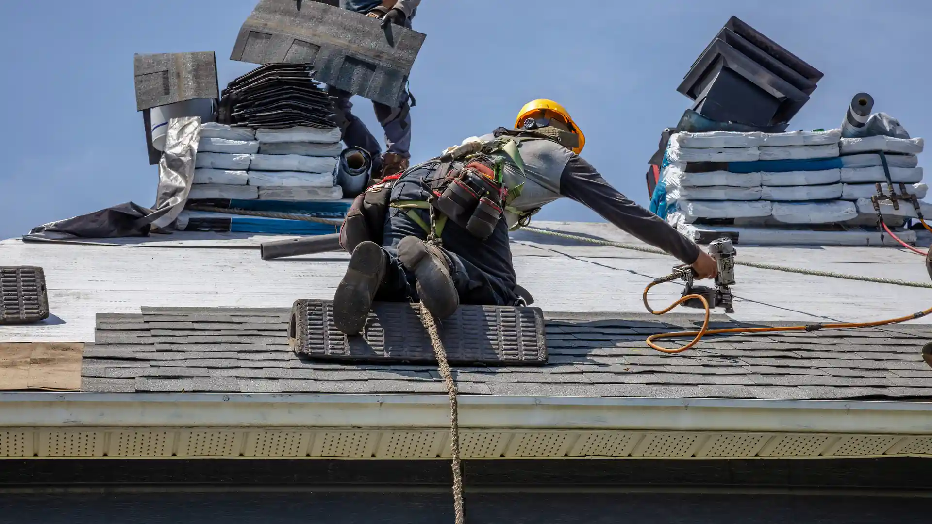 A roofer installing shingles on a residential roof