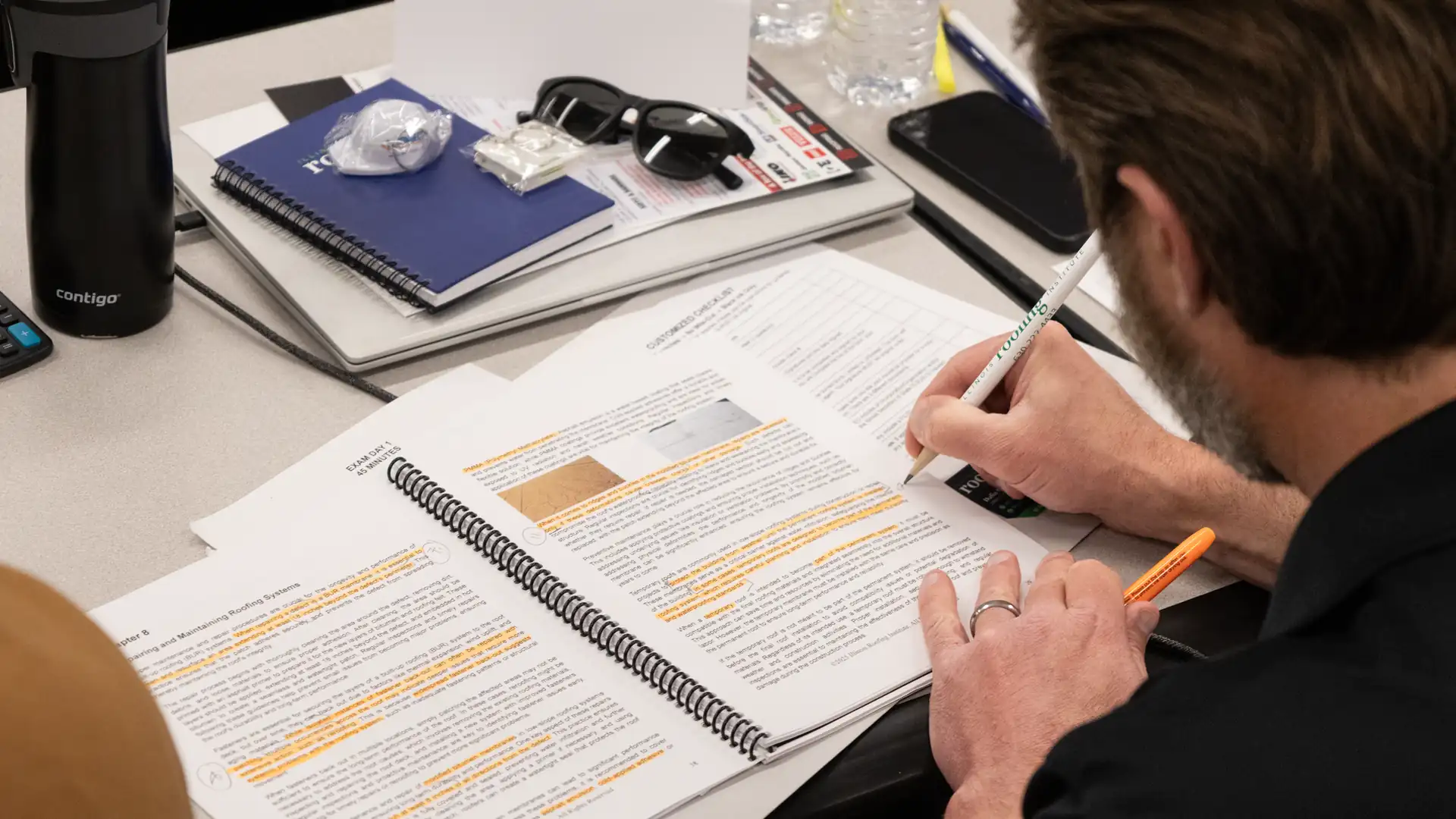 A student taking notes in the class workbook