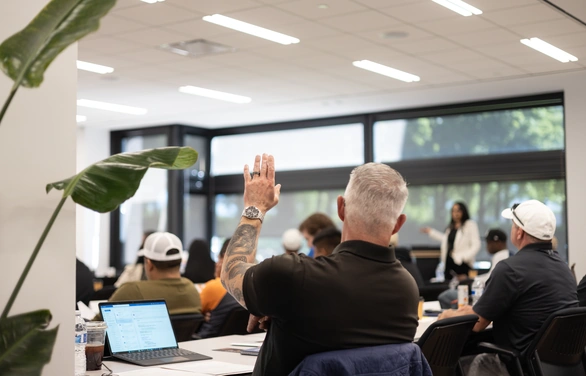 A student raising his hand to ask a question in an Illinois Roofing Institute class