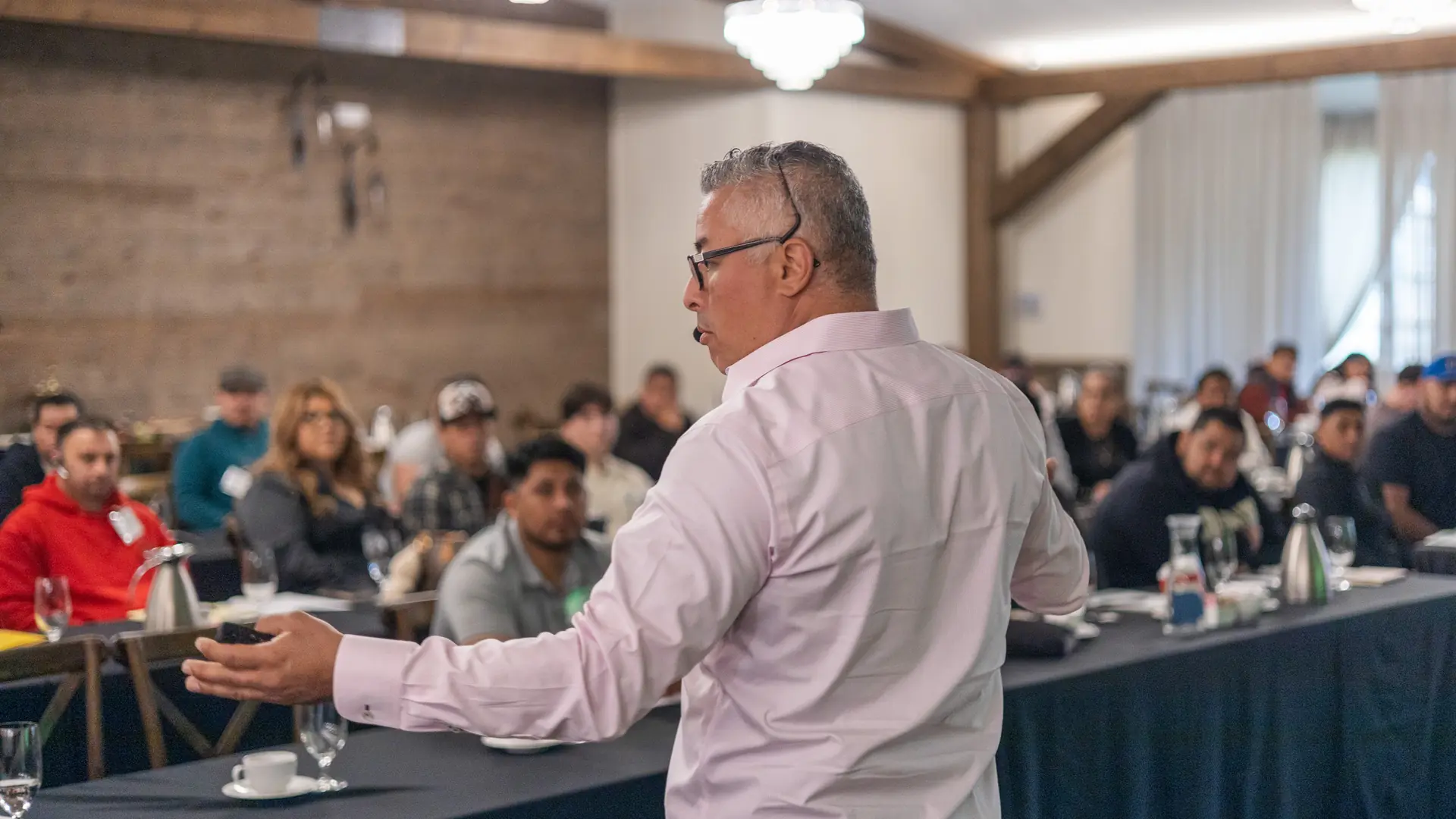 An instructor with a headset microphone addressing a full room of roofing contractors at a Roof CoLab sales training