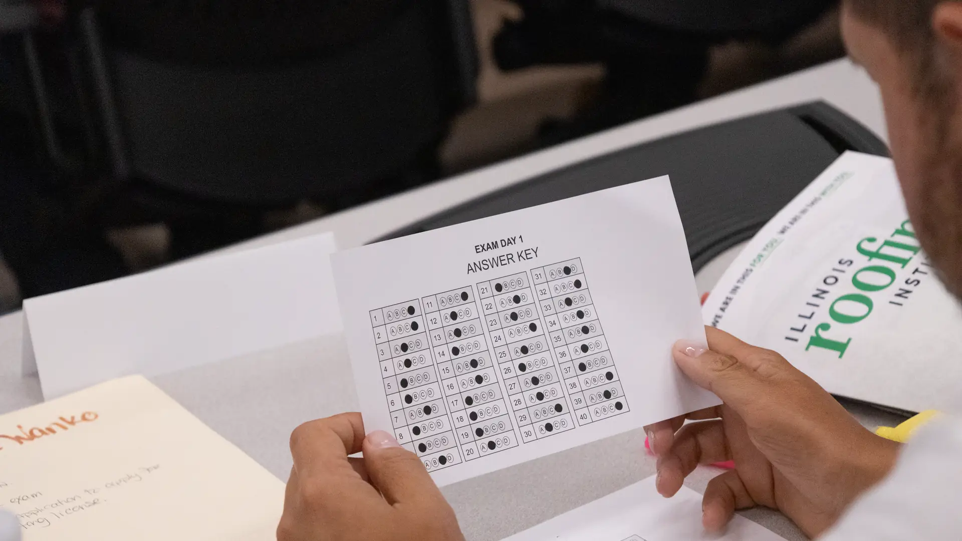 Alumna revisando la hoja de respuestas de un examen de práctica de roofing en clase