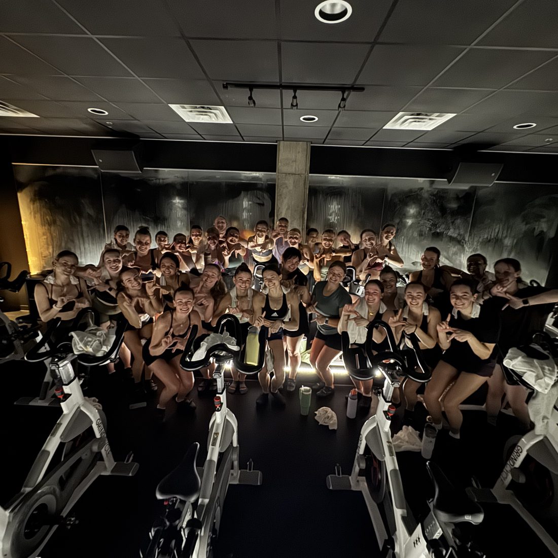 A packed cycle room posing for a photo after a private ride