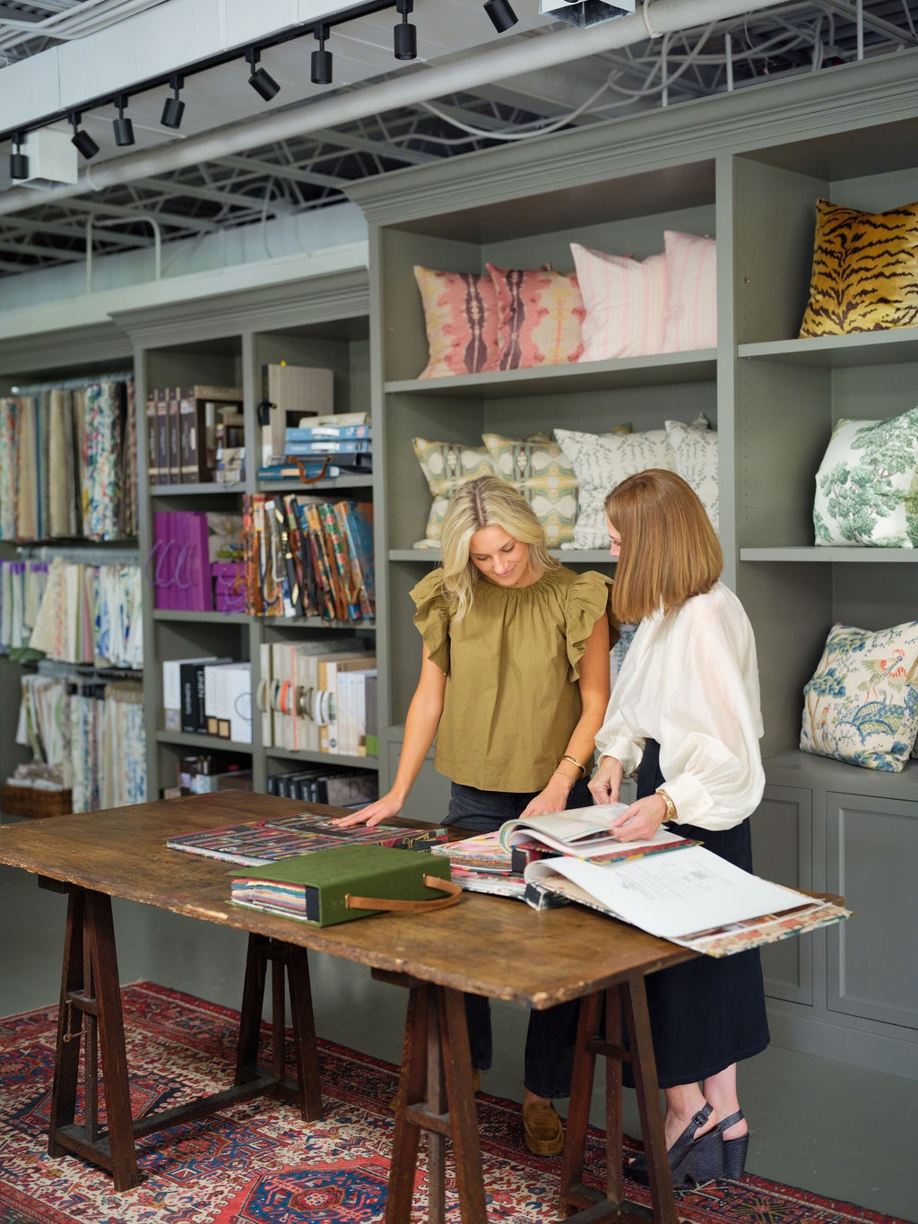 Two designers reviewing samples at a wooden worktable in the showroom