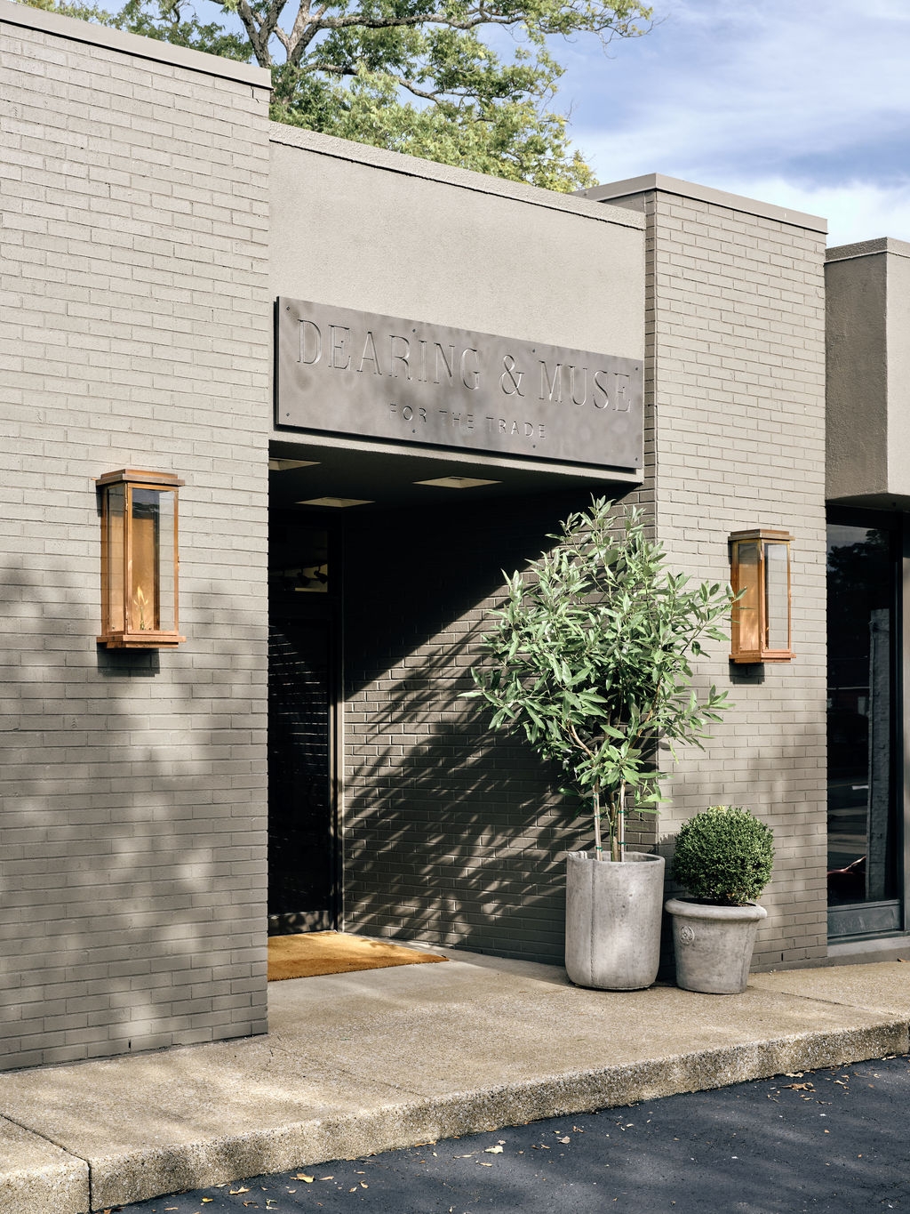 Showroom entrance with a potted olive tree beside the front door