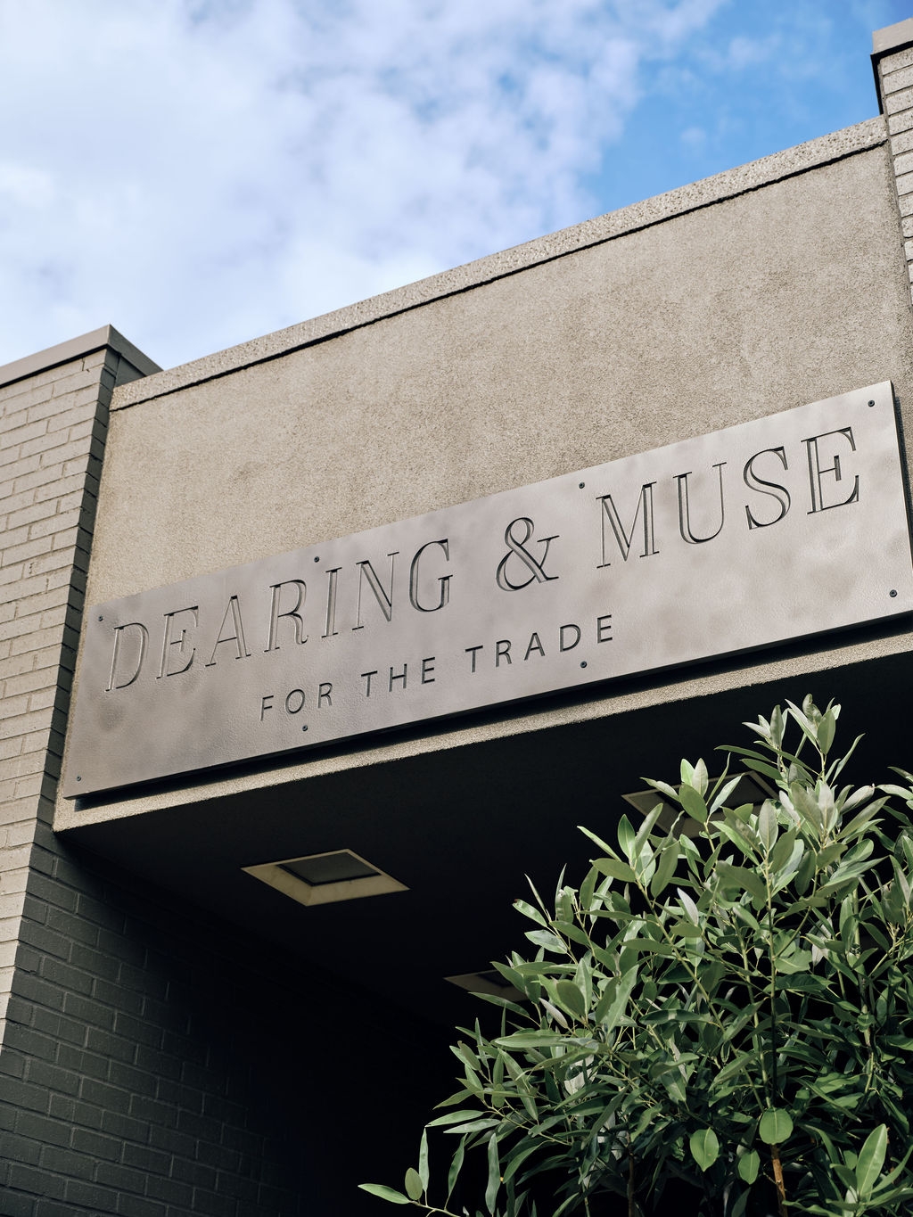 The Dearing & Muse storefront sign, carved in stone above the entrance, with greenery below
