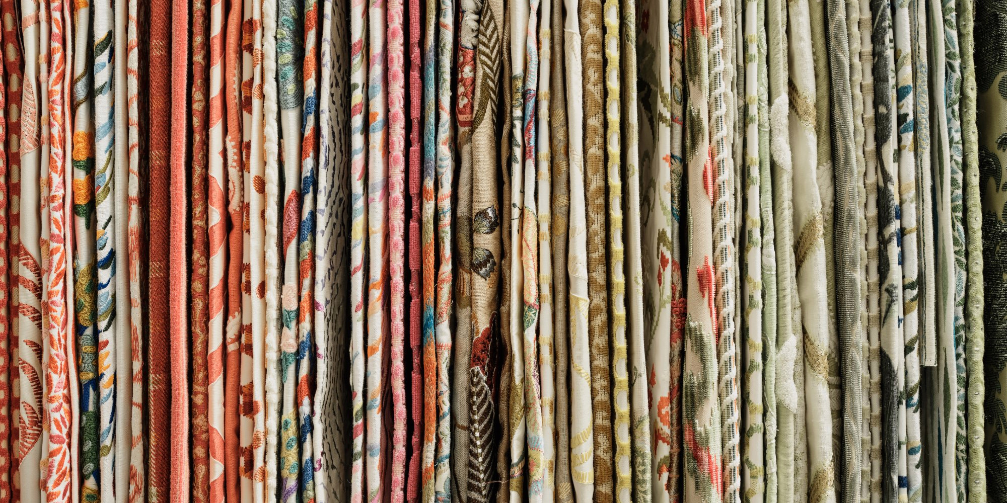 Row of hanging fabric samples in reds, greens and florals