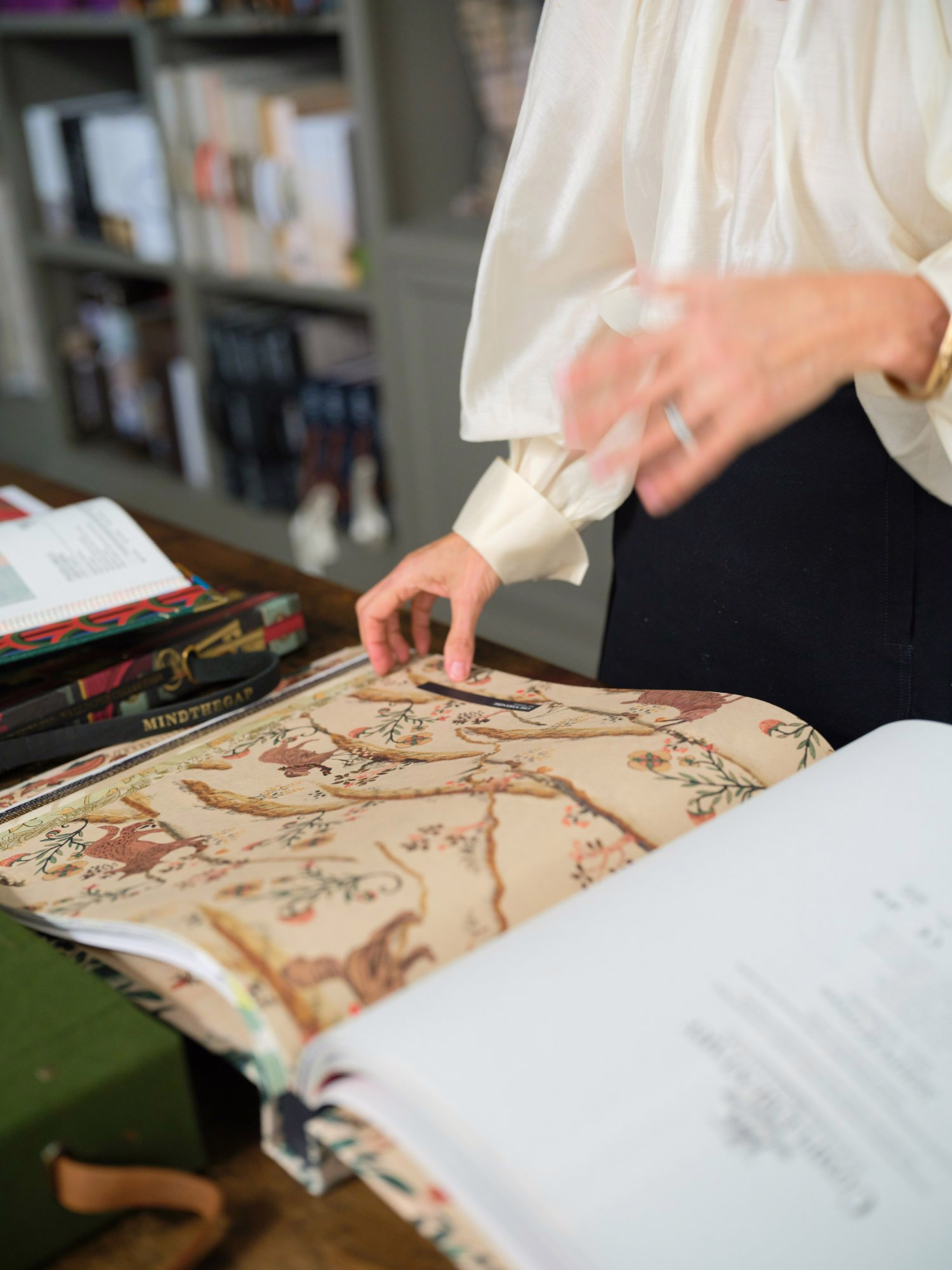 Hands turning the pages of a floral fabric sample book on the showroom table