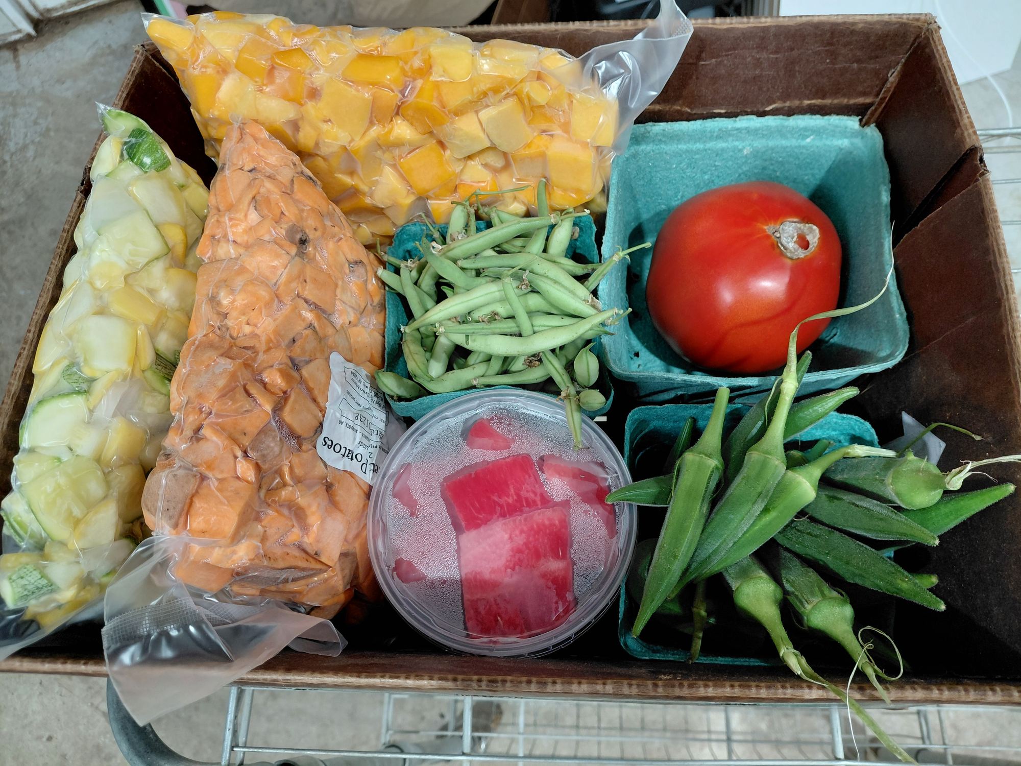 A FRESH Box with frozen squash and sweet potatoes, peas, okra and a tomato from FRESH Network