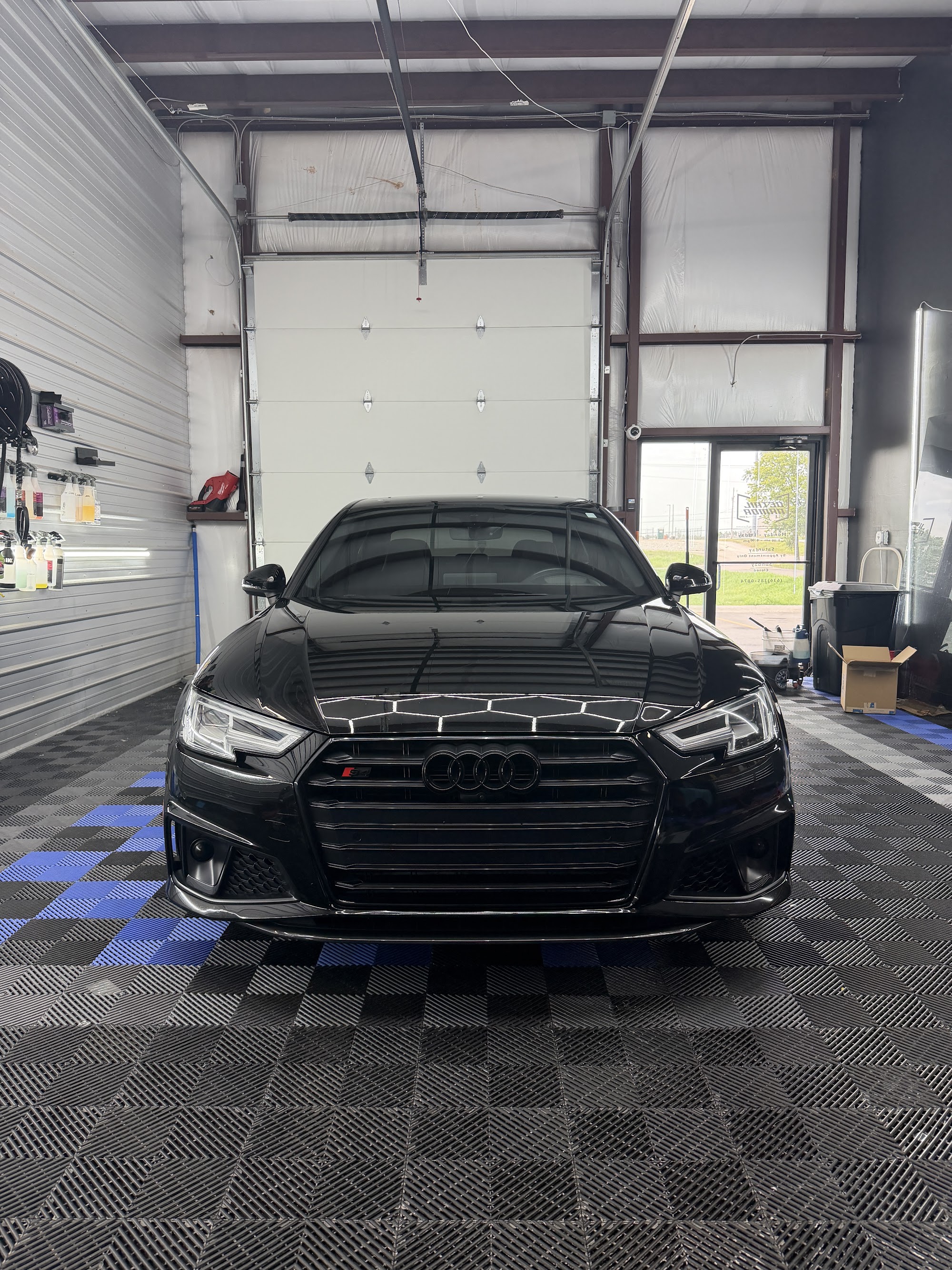 Black Audi A6 with a ceramic coating and tinted windows reflecting hexagon lights