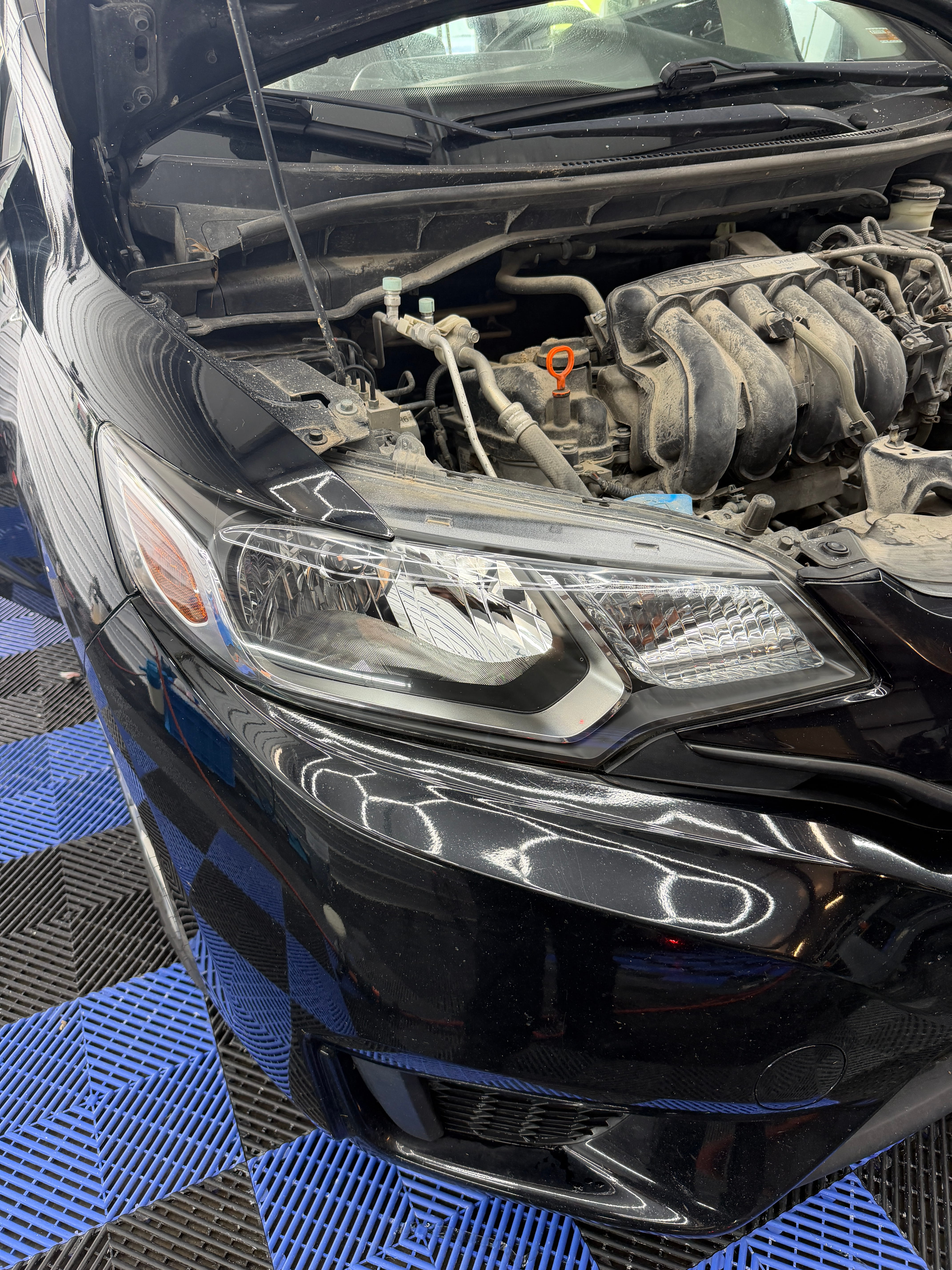 Crystal clear headlight on a black car after headlight restoration at Detail Armor