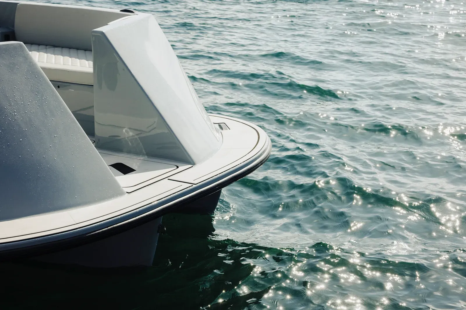 Close-up view of a white and gray paddle boat floating on water with sunlight reflecting on the ripples.
