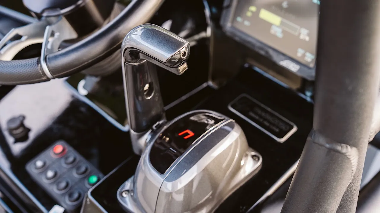 Close-up of a sleek, metallic boat throttle control lever with a red digital display showing the letter 'N' for neutral, surrounded by black glossy panels and other control buttons.