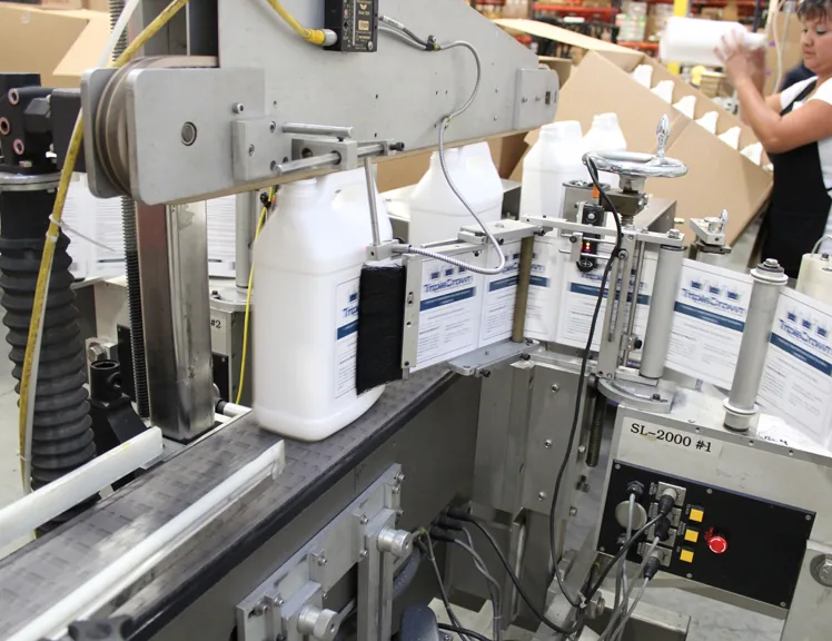 Pressure sensitive labels being applied to HDPE jugs on an Inmark decoration line