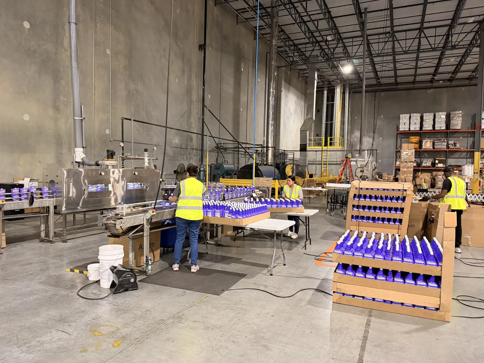 Inmark team packing filled bottles into display cartons at the end of a filling line