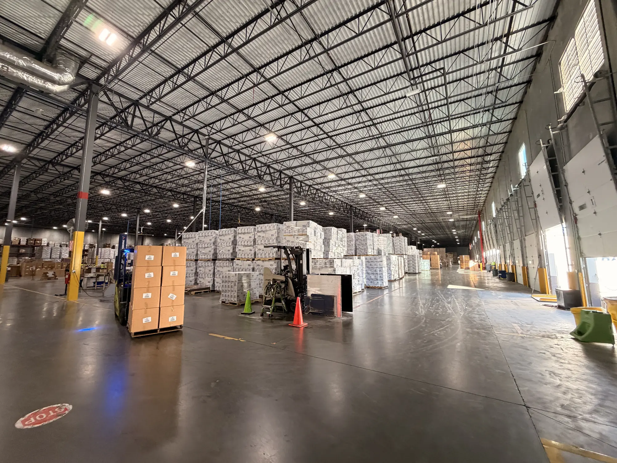Inmark warehouse aisle with palletized stock, a forklift and loading dock doors