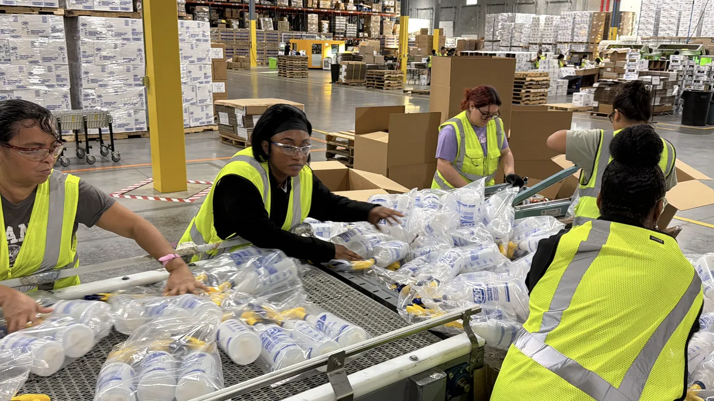 Inmark kitting team packing bottles and sprayers at a conveyor