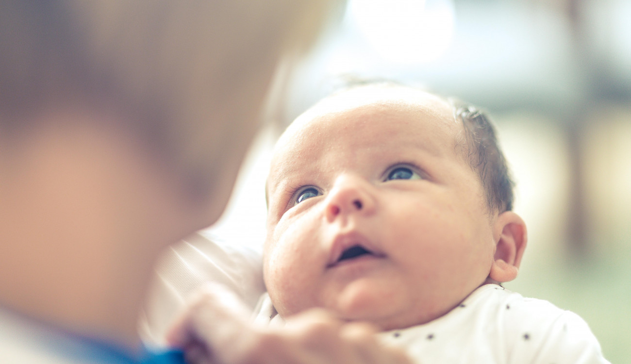 A newborn baby looking up at a carer