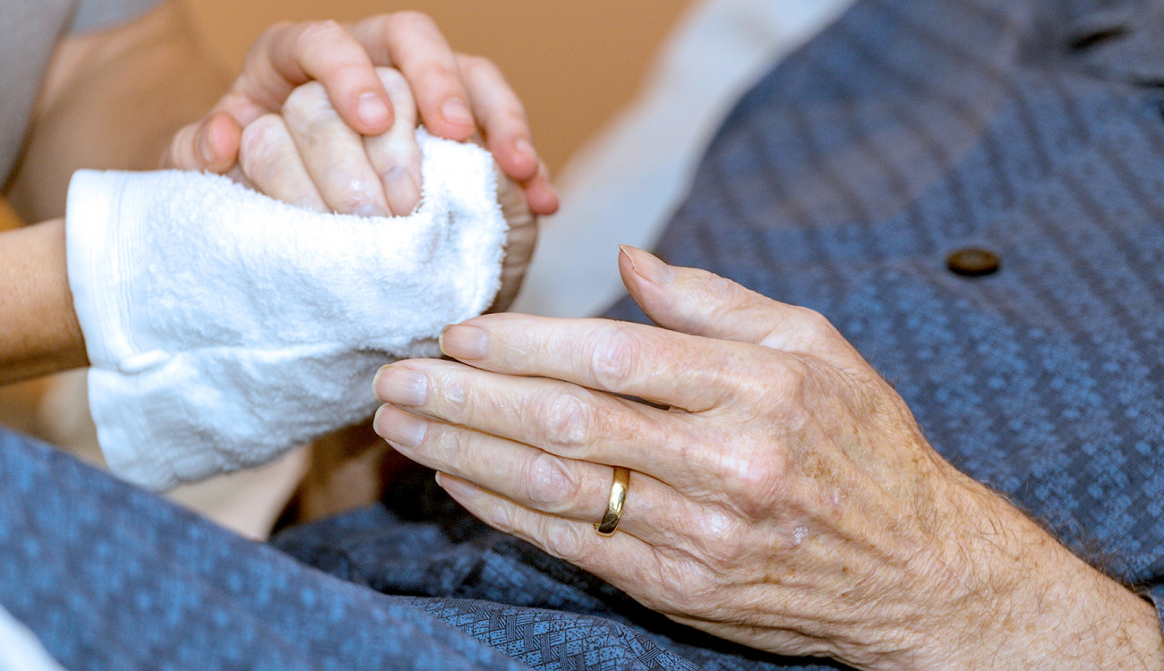 Hands gently holding the hand of an older person