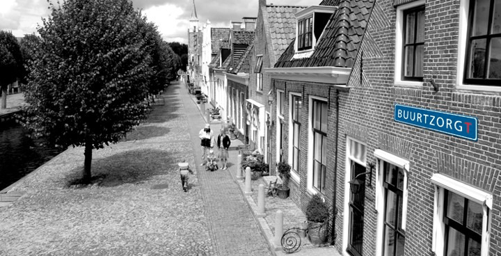 A Dutch street with a blue Buurtzorg sign on a brick house