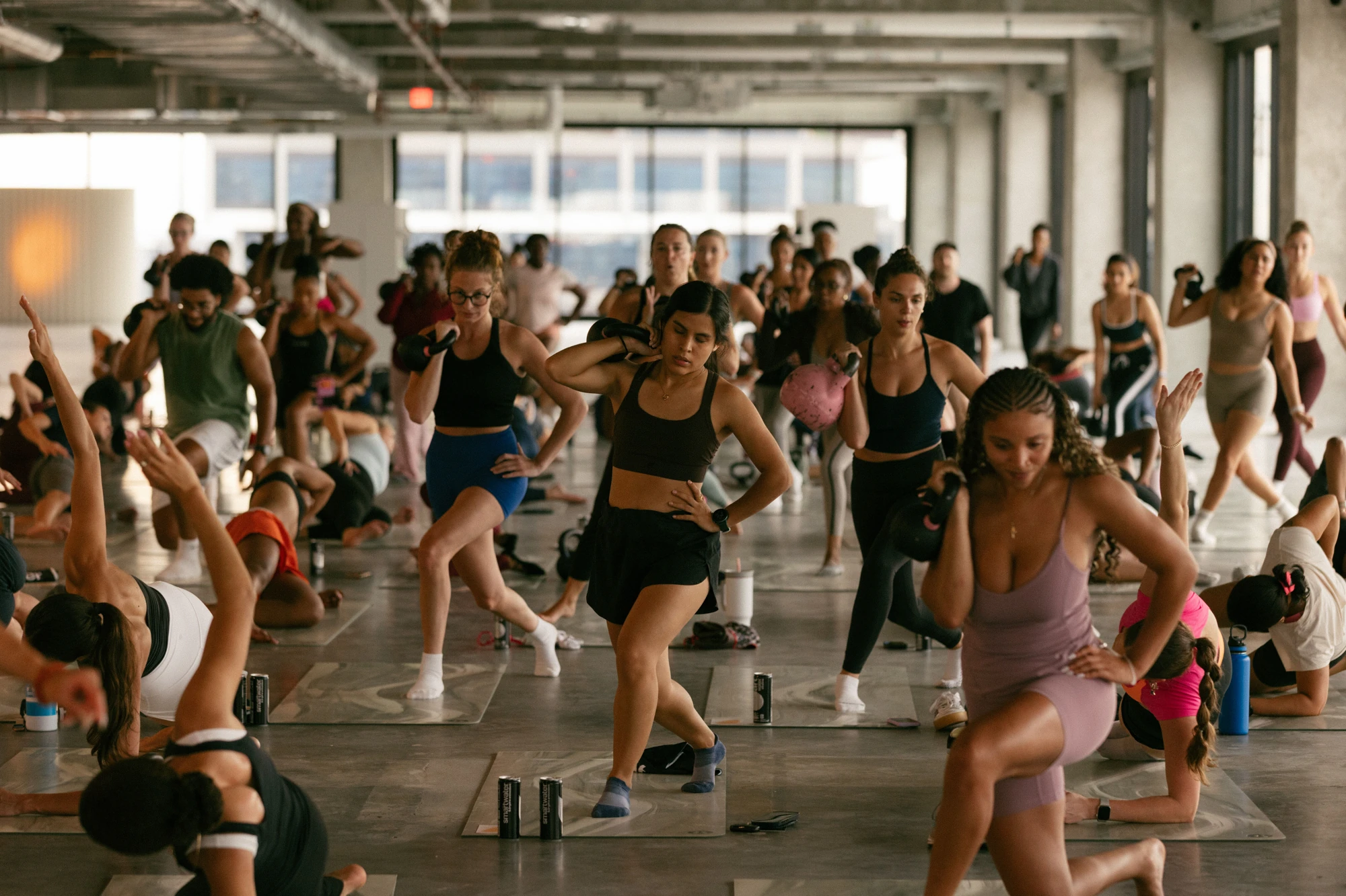 Participants moving through a lunge together in a bright mat class.