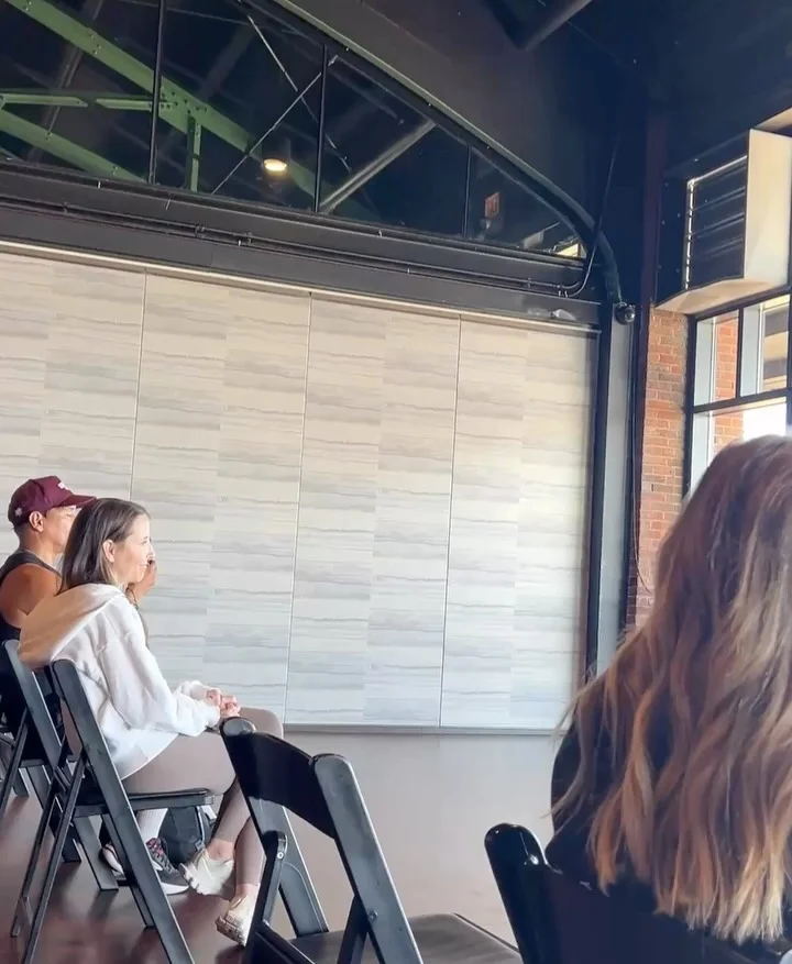 Attendees listening to a discussion beneath the brick arcade.