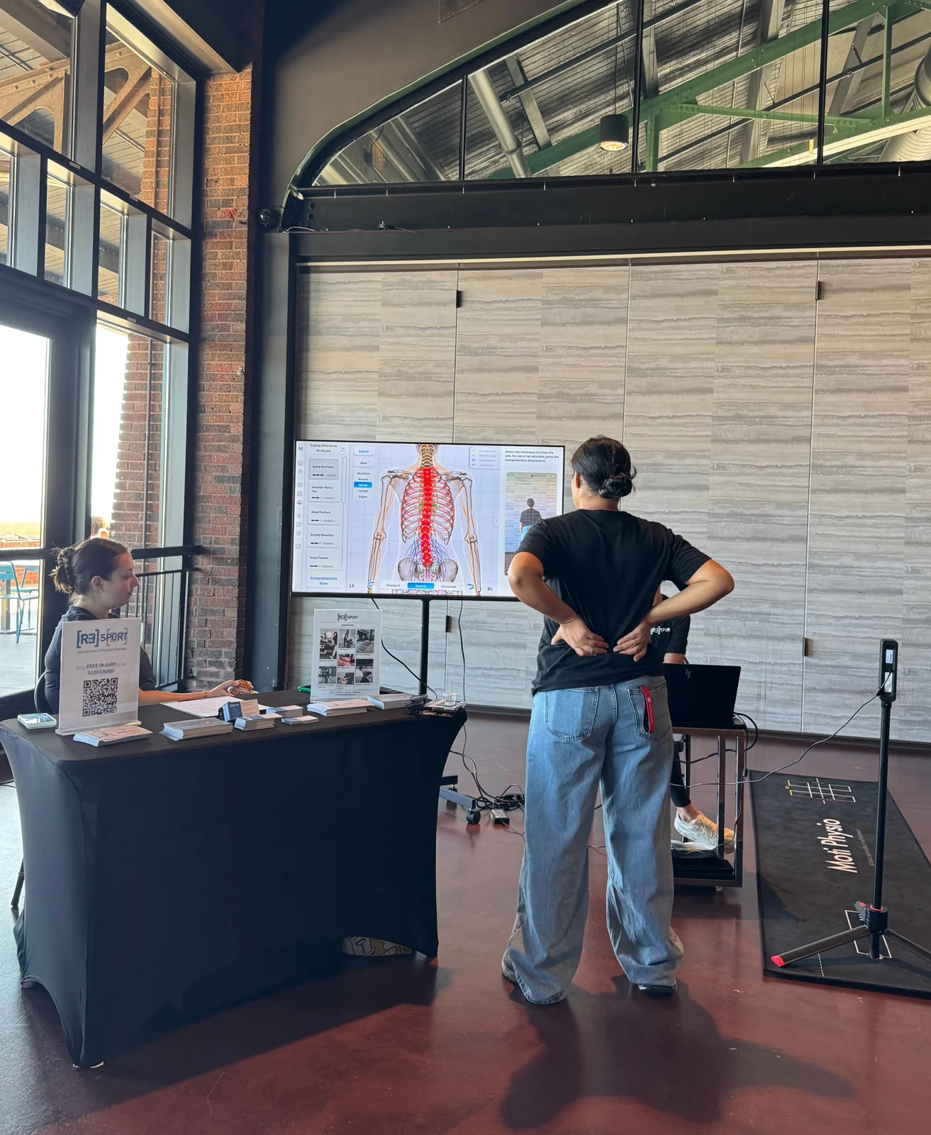 A presenter using a spine anatomy display at a recovery booth.