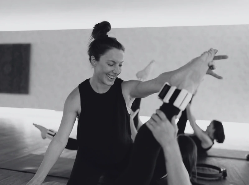 An instructor smiling and gesturing during a mat session.