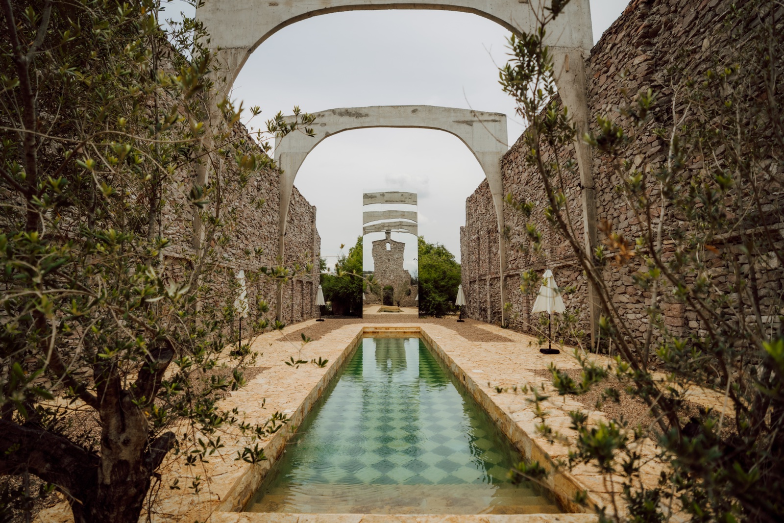 pasillo de arcos de piedra y estanque en hacienda la bartola