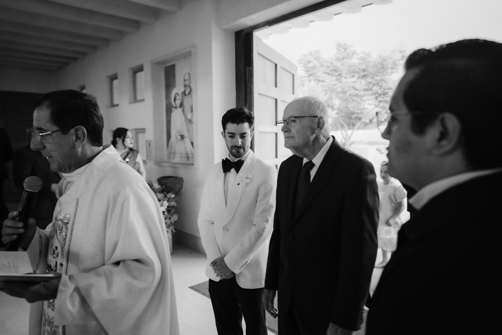 novia sonriendo junto a los invitados, en blanco y negro