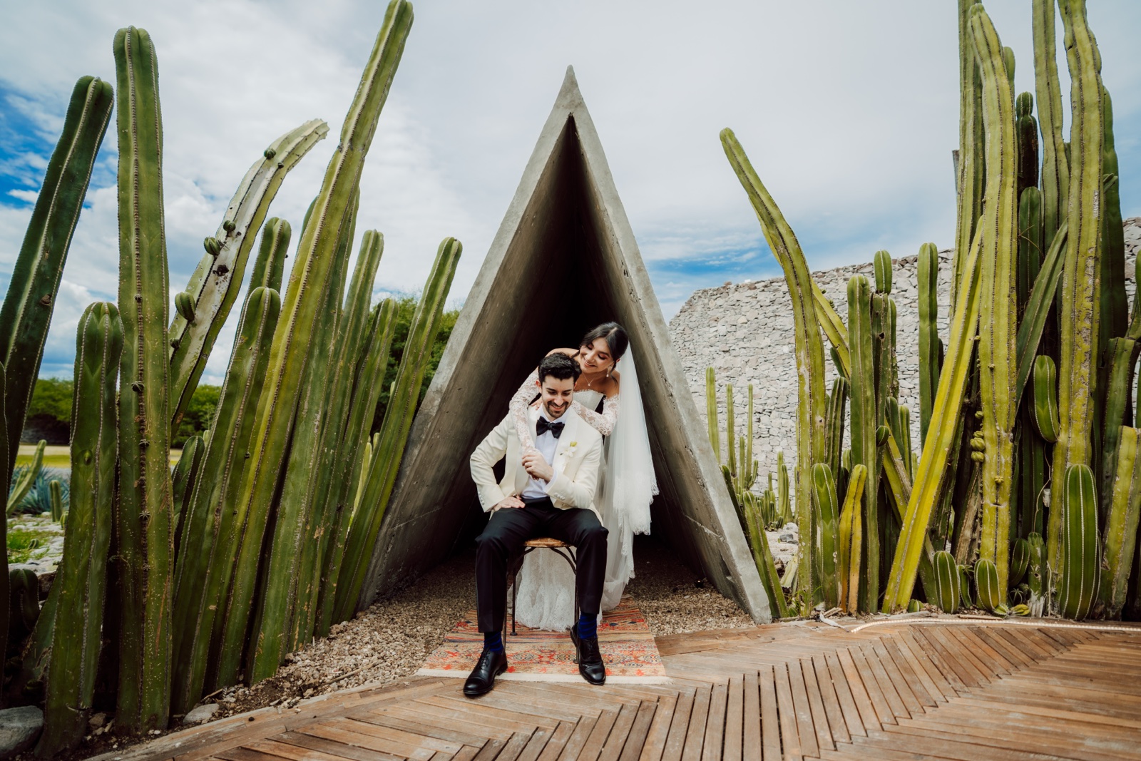 novios frente a una estructura triangular en el jardín de cactus