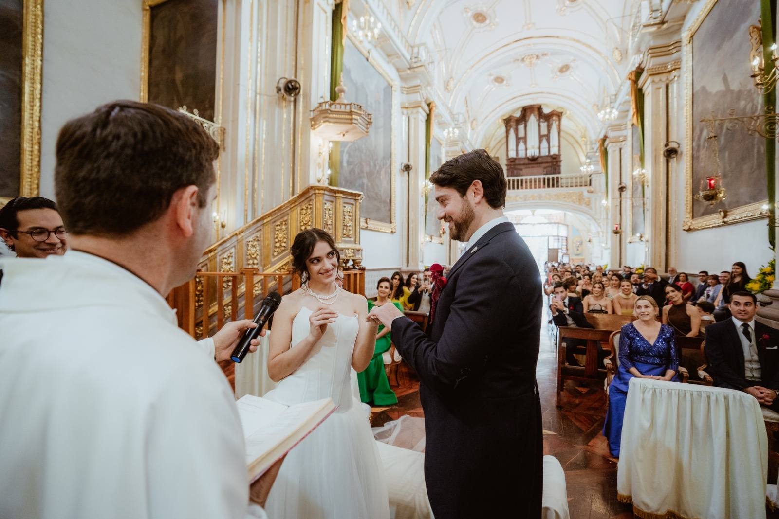 novios frente al sacerdote durante el intercambio de anillos