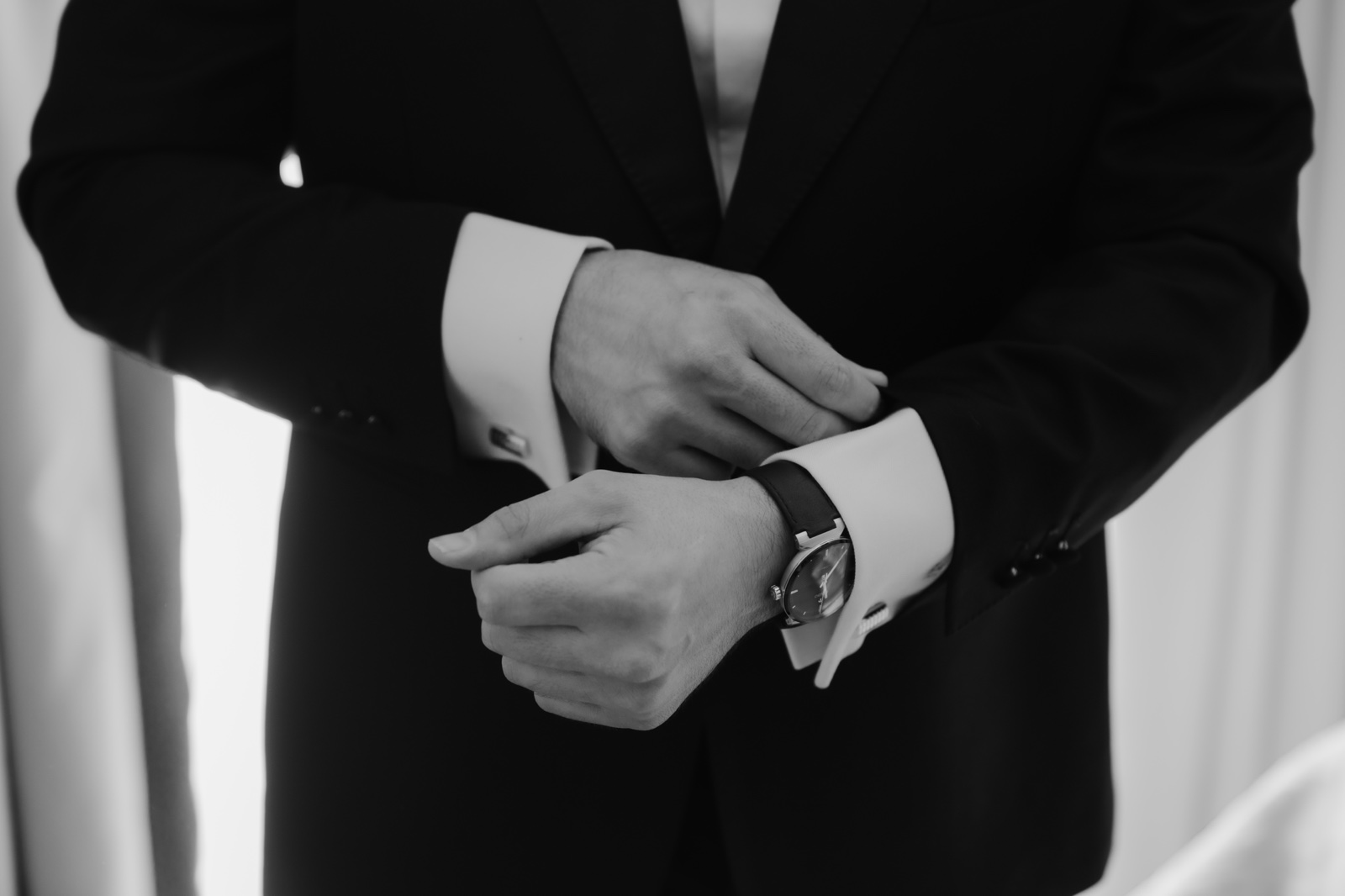 detalle del novio ajustándose el traje, en blanco y negro