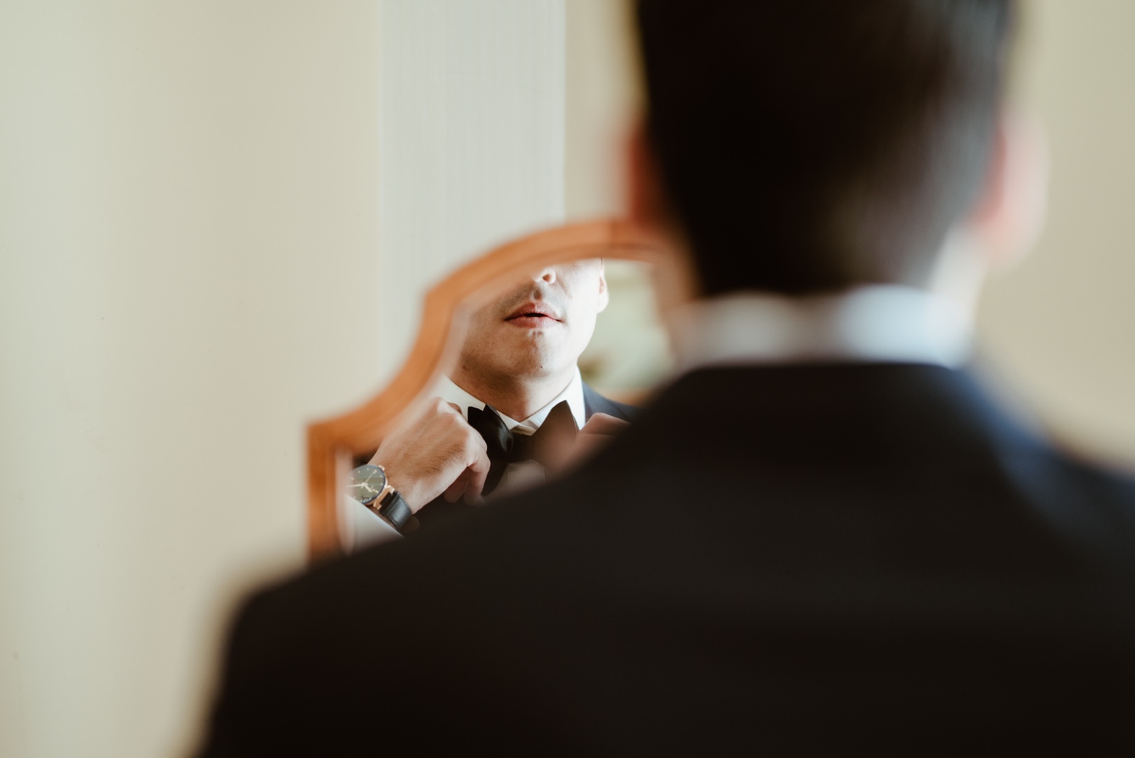novio ajustándose el cuello del traje frente al espejo