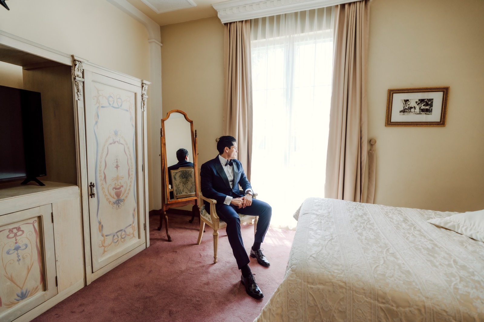 novio preparándose junto a la cama de la habitación