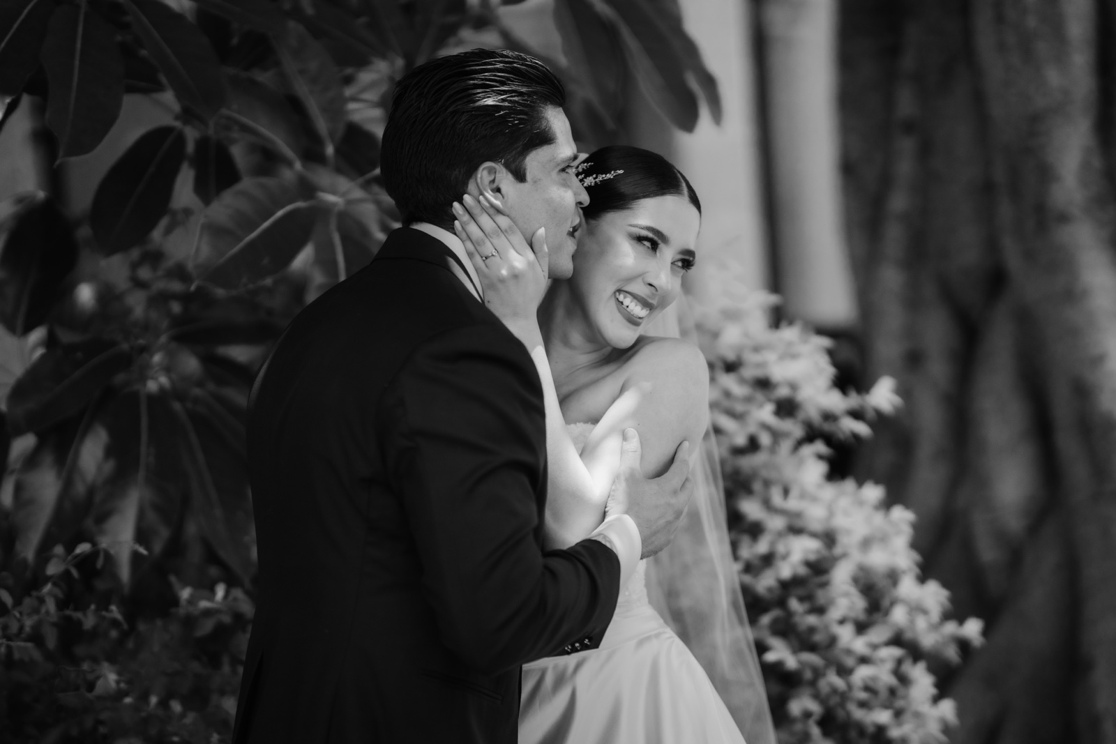 novios abrazados entre plantas, en blanco y negro
