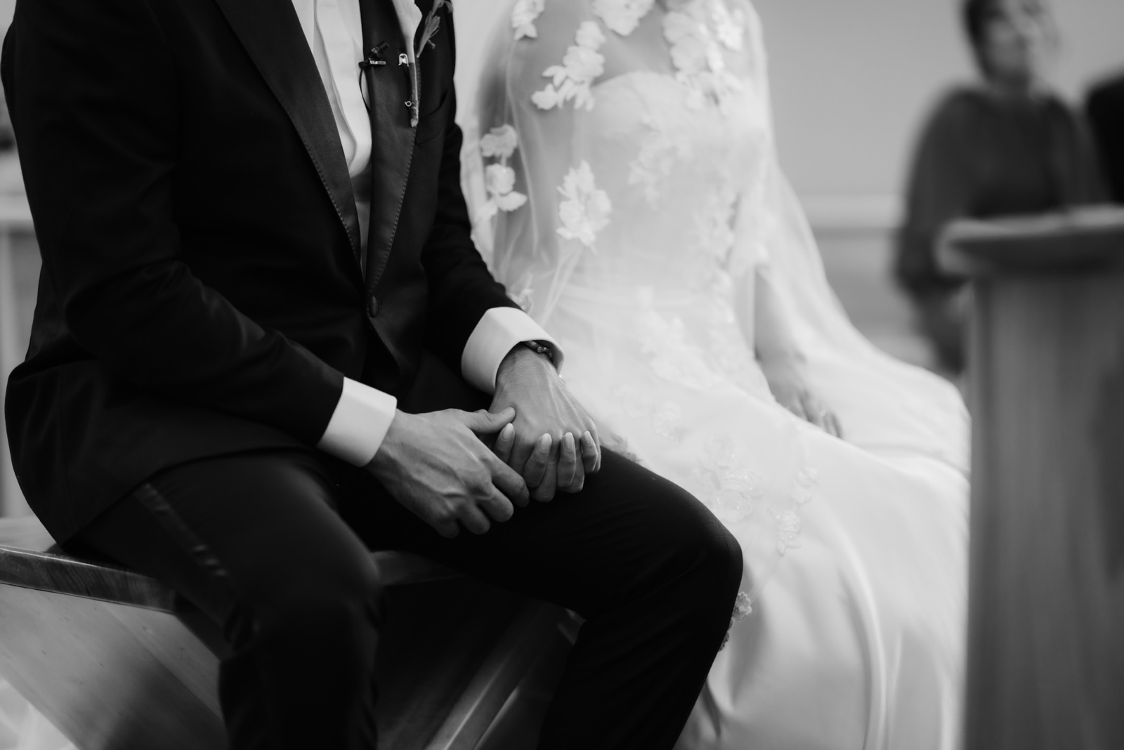 detalle del vestido y traje de los novios sentados, en blanco y negro