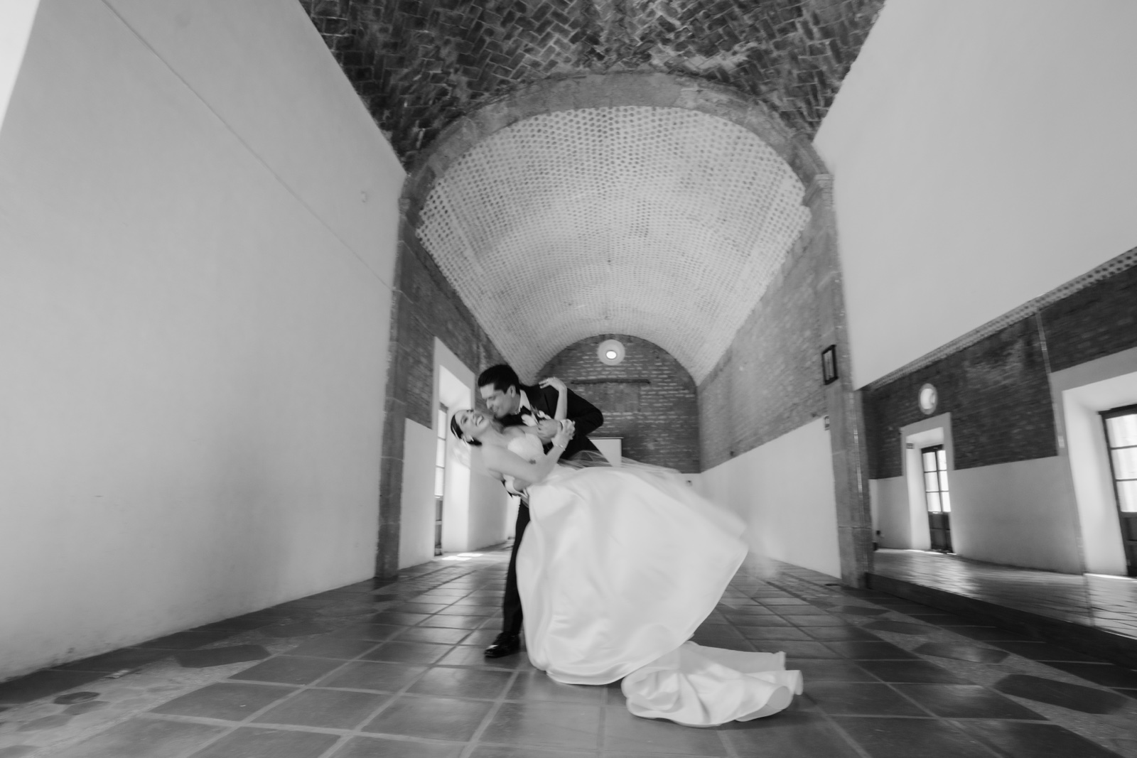 novios abrazados en un salón abovedado, en blanco y negro