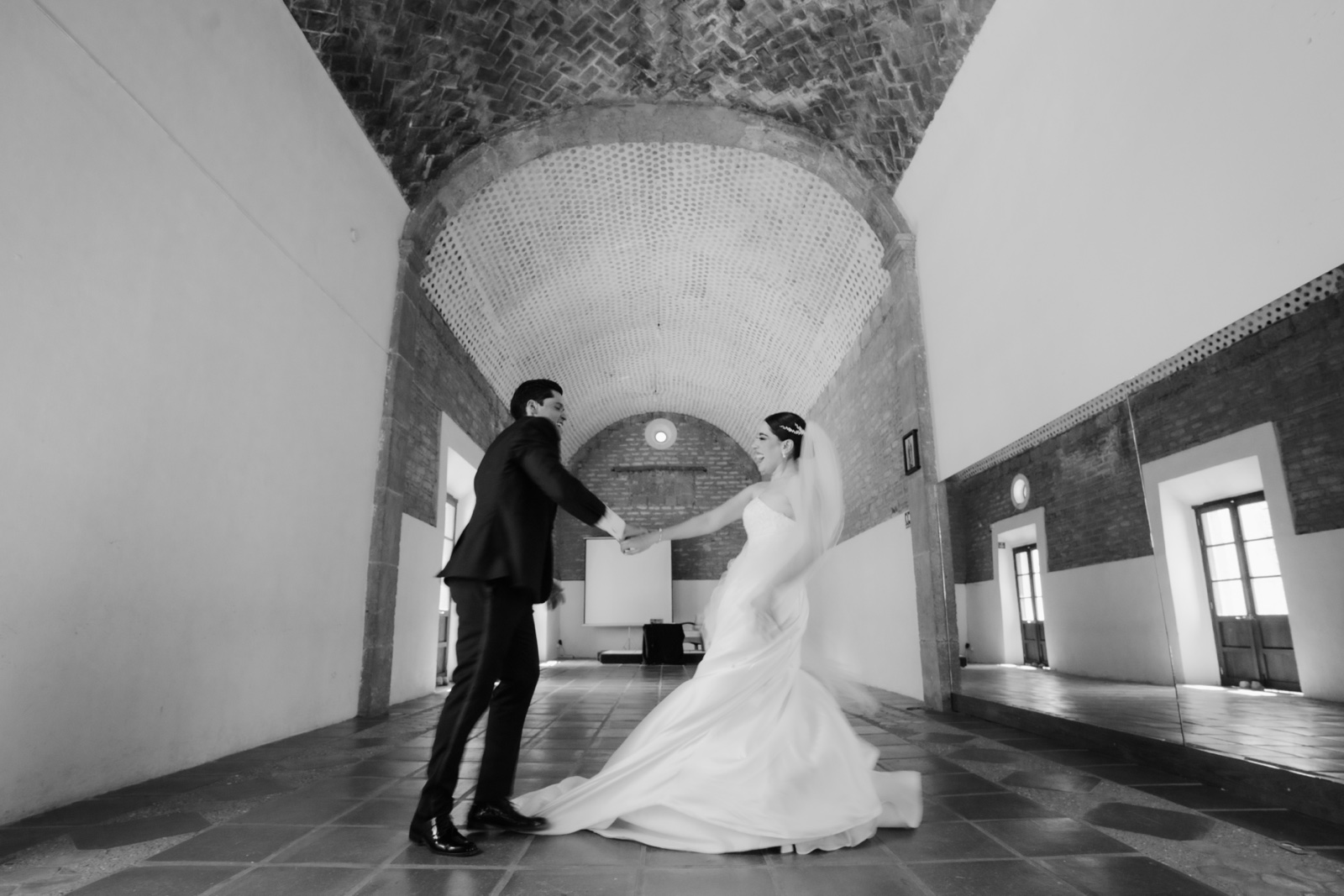 novios juntos en un salón abovedado, en blanco y negro