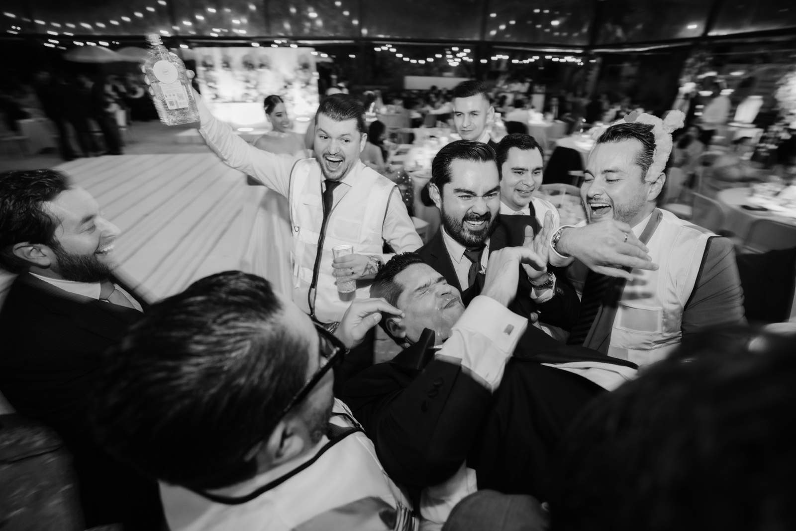 invitados sonriendo junto al novio, en blanco y negro
