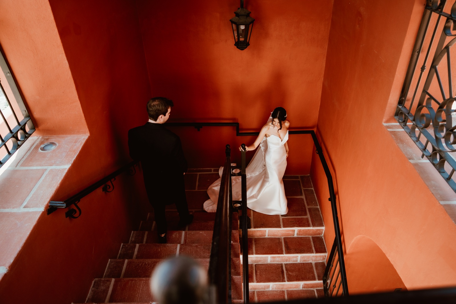 novios en una escalera entre muros rojizos