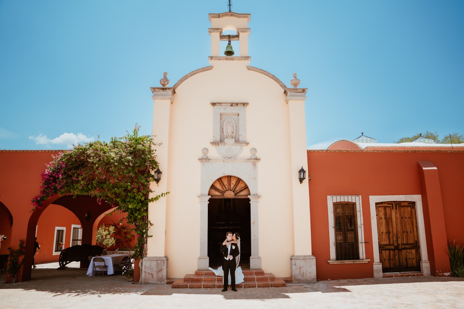 fachada de una capilla blanca entre muros rojizos