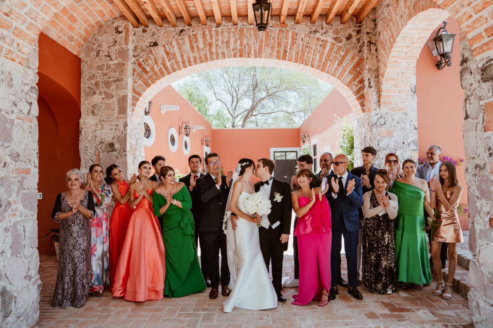 novios e invitados reunidos bajo un arco en el patio