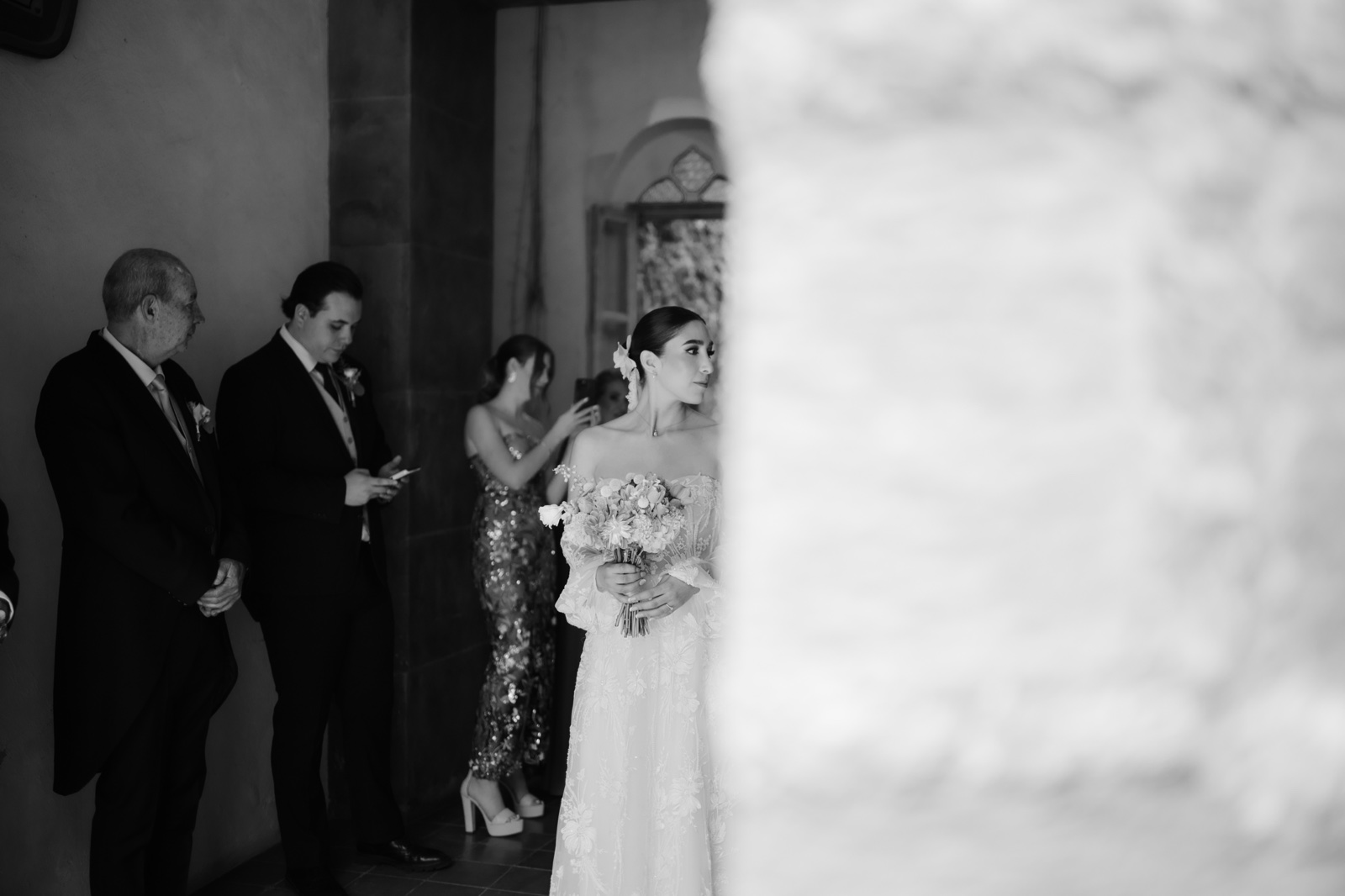 invitados esperando a la novia junto a un muro de piedra