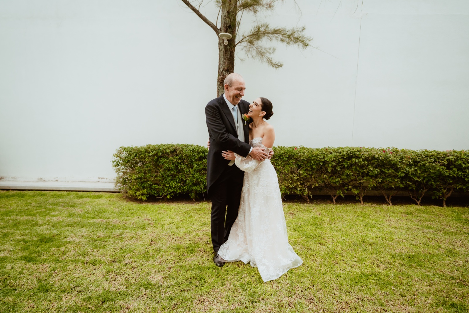 novios abrazados junto a un árbol en el jardín