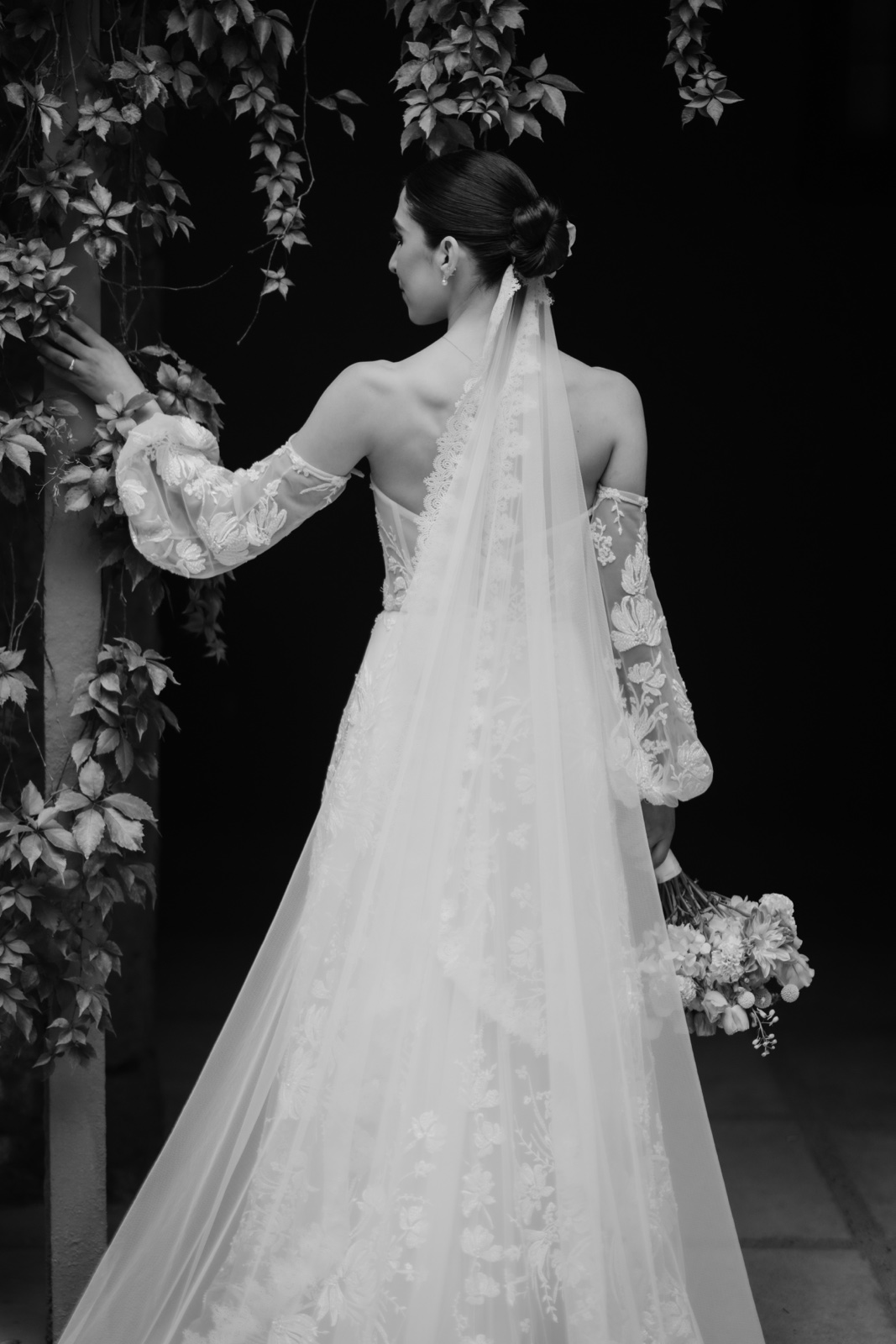 novia mostrando su vestido de espaldas, en blanco y negro