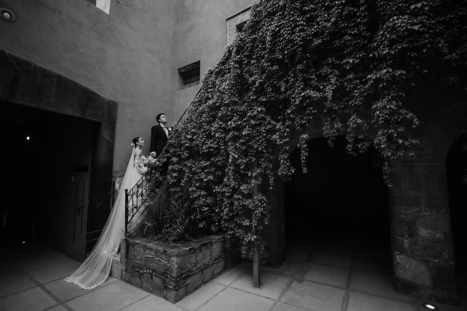 novios recorriendo el patio de piedra, en blanco y negro
