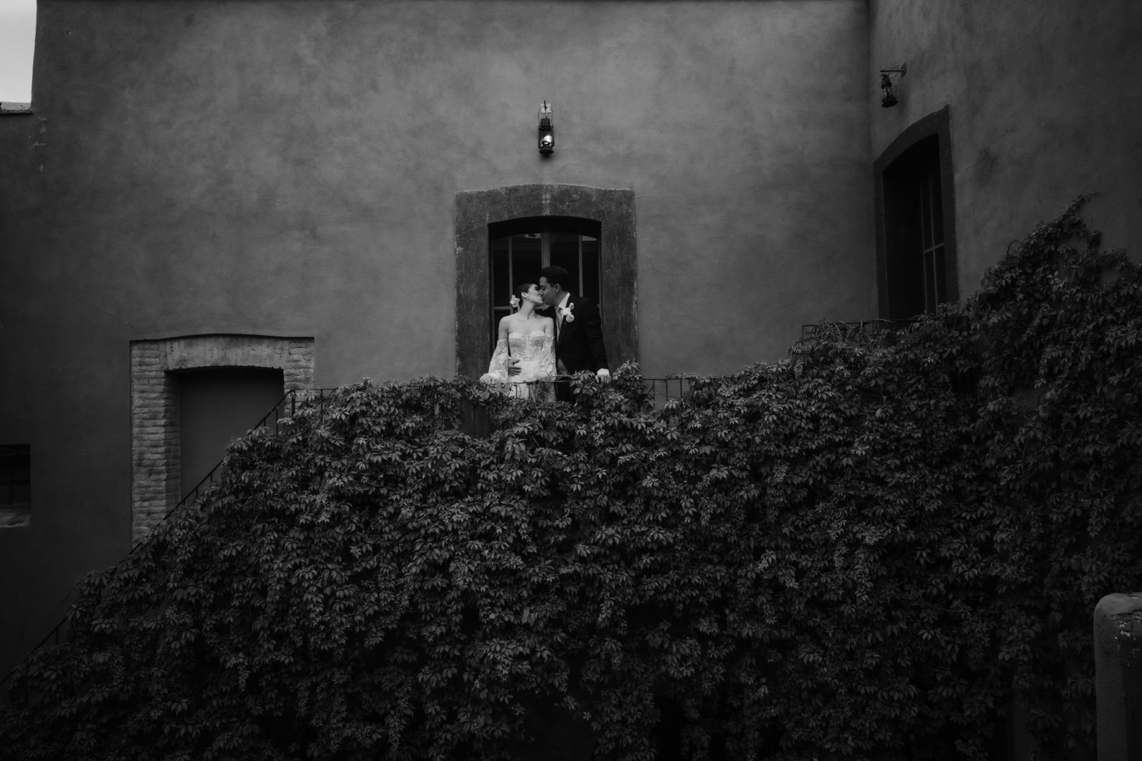 novios besándose junto a una ventana, en blanco y negro