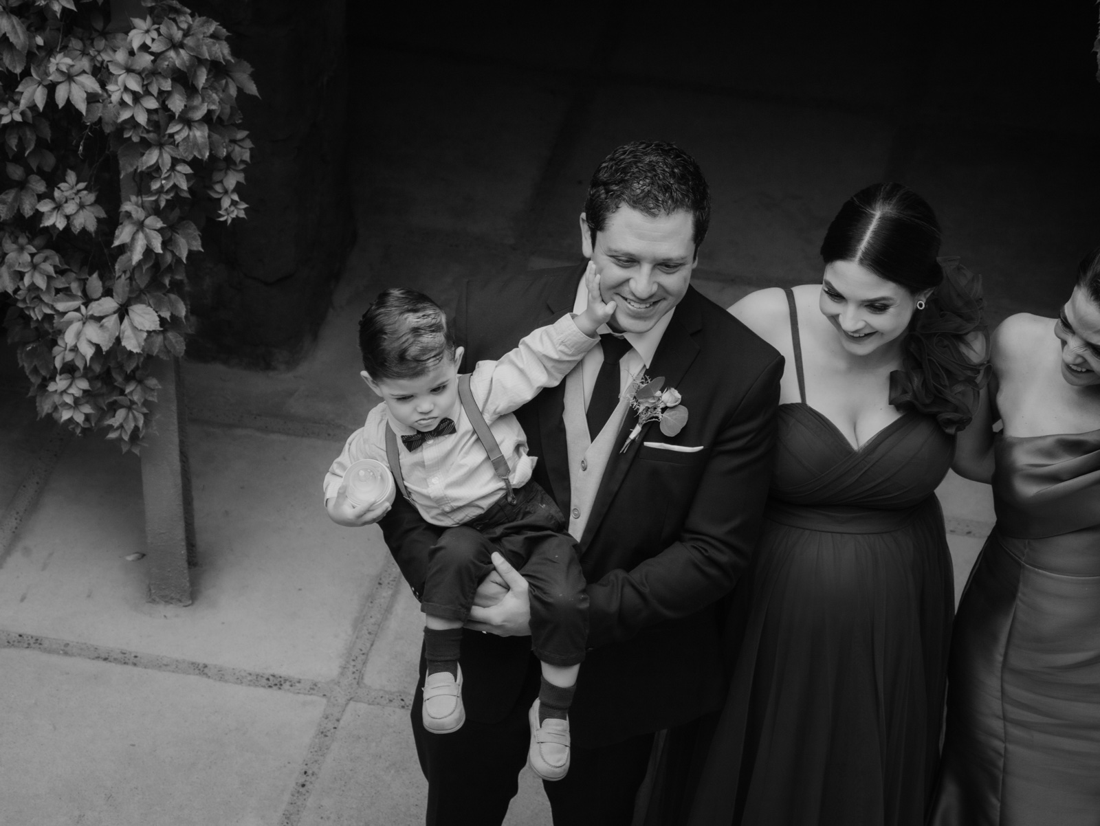 novio ajustando su traje junto a una invitada, en blanco y negro