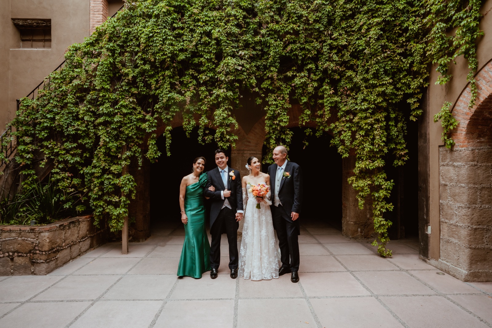 novios posando con invitados en el patio